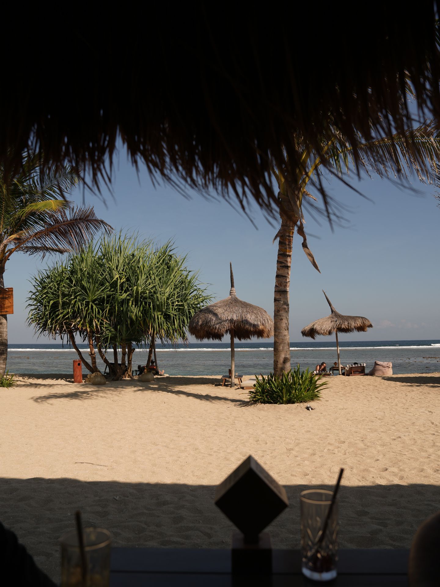Tampah Bay beach — thatched umbrellas, coconut palms and calm turquoise water on white sand