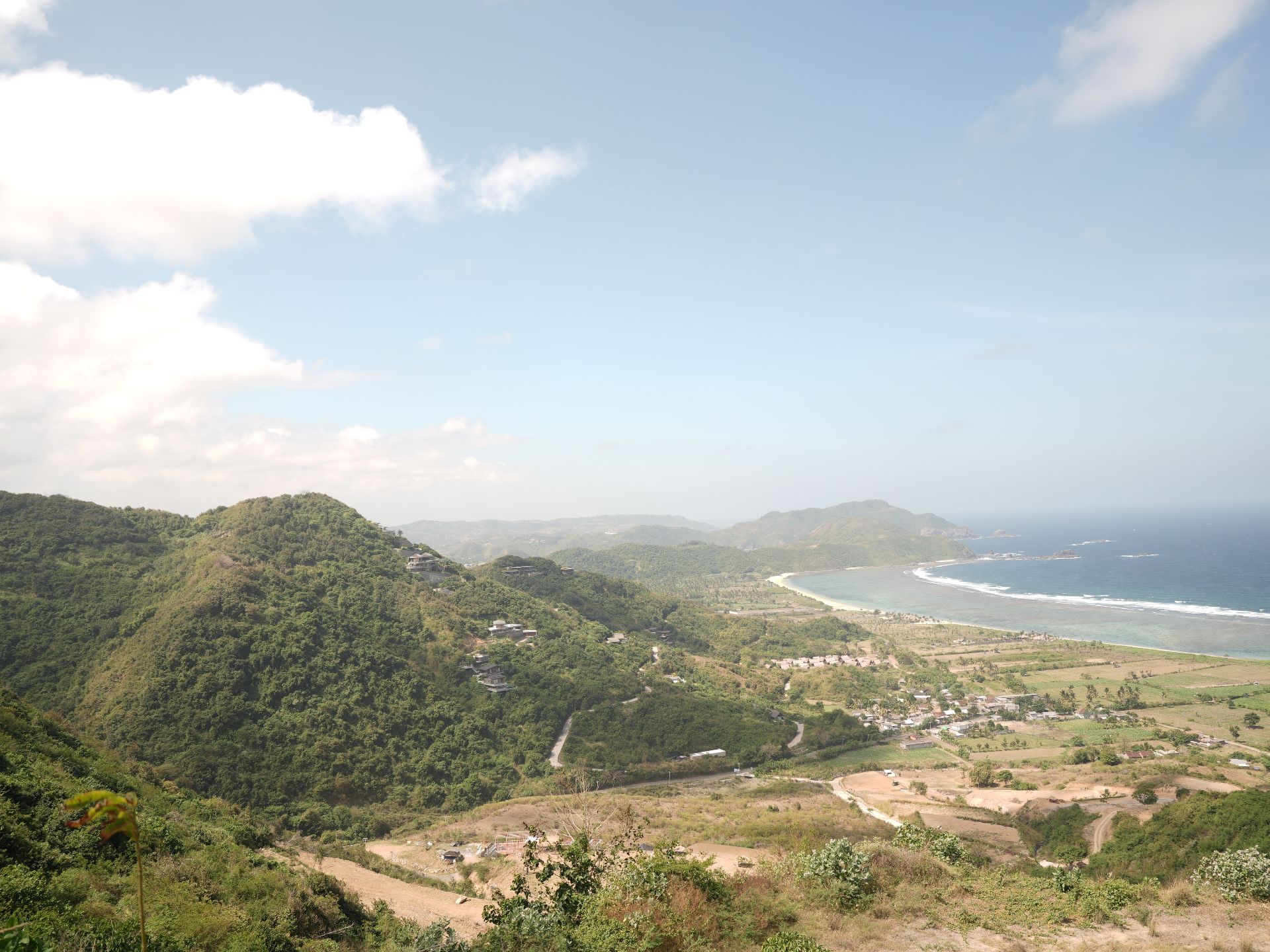 Hillside view over South Lombok — green headlands meeting a crescent bay